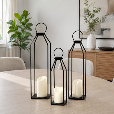 A Set of 3 Black Metal modern farmhouse lanterns includes Flickering Flameless Candles with a 6hr Timer for front-porch and outdoor decor as well as indoor, patio, garden, fireplace, or Christmas displays.