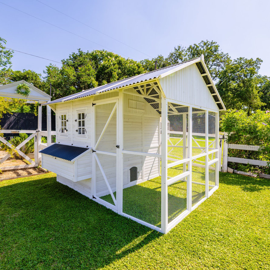 A white backyard chicken coop with an enclosed run.