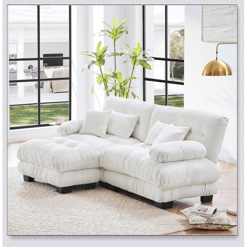 Luxueux canapé en chenille pour le salon avec plusieurs coussins et repose-pieds convertible, pour plus de confort et de style.