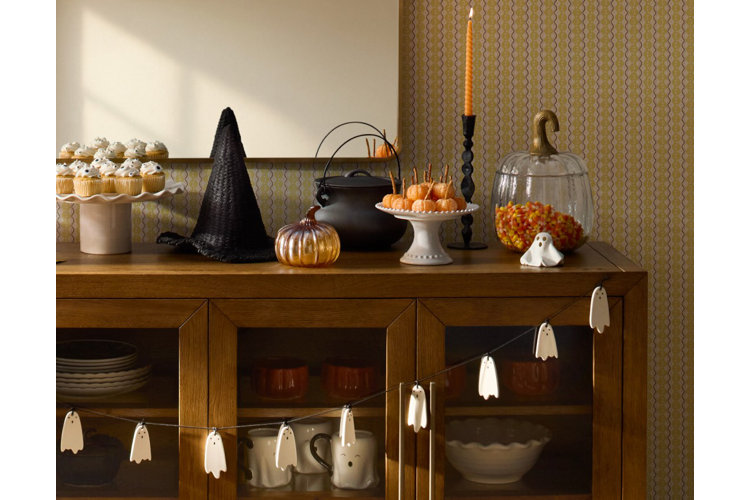 vintage halloween aesthetic buffet table with vintage halloween decor a wicker witches hat glass pumpkins a traditional candle stick and candy corn