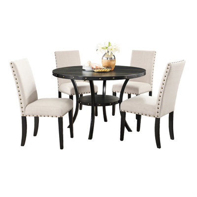 5 pièces en bois. Table ronde en bois à finition grain de café avec pieds en métal, chaises cloutées en tissu brun clair et revêtement en coton pour la pièce. 5 Comprend des chaises. Possède un plateau et des pieds. Caractéristique Lin, laiton