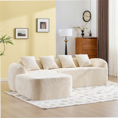 Beige Chenille L-Shaped Compressed Sofa That Goes Well With Any Living Room. It Features High-Elastic Sponge For A Comfortable Sitting Feel,  Curved Armrests And Four Throw Pillows.
