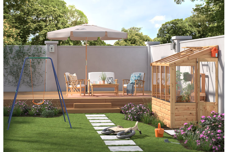 Large backyard with a lean-to greenhouse against the wall. A raised wood deck with an umbrella and conversation set. Blue swing on the grass