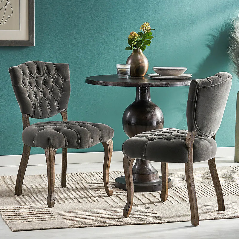 Ensemble de deux chaises capitonnées d'inspiration européenne avec pieds sculptés à la main et revêtement capitonné pour des solutions d'assise polyvalentes.