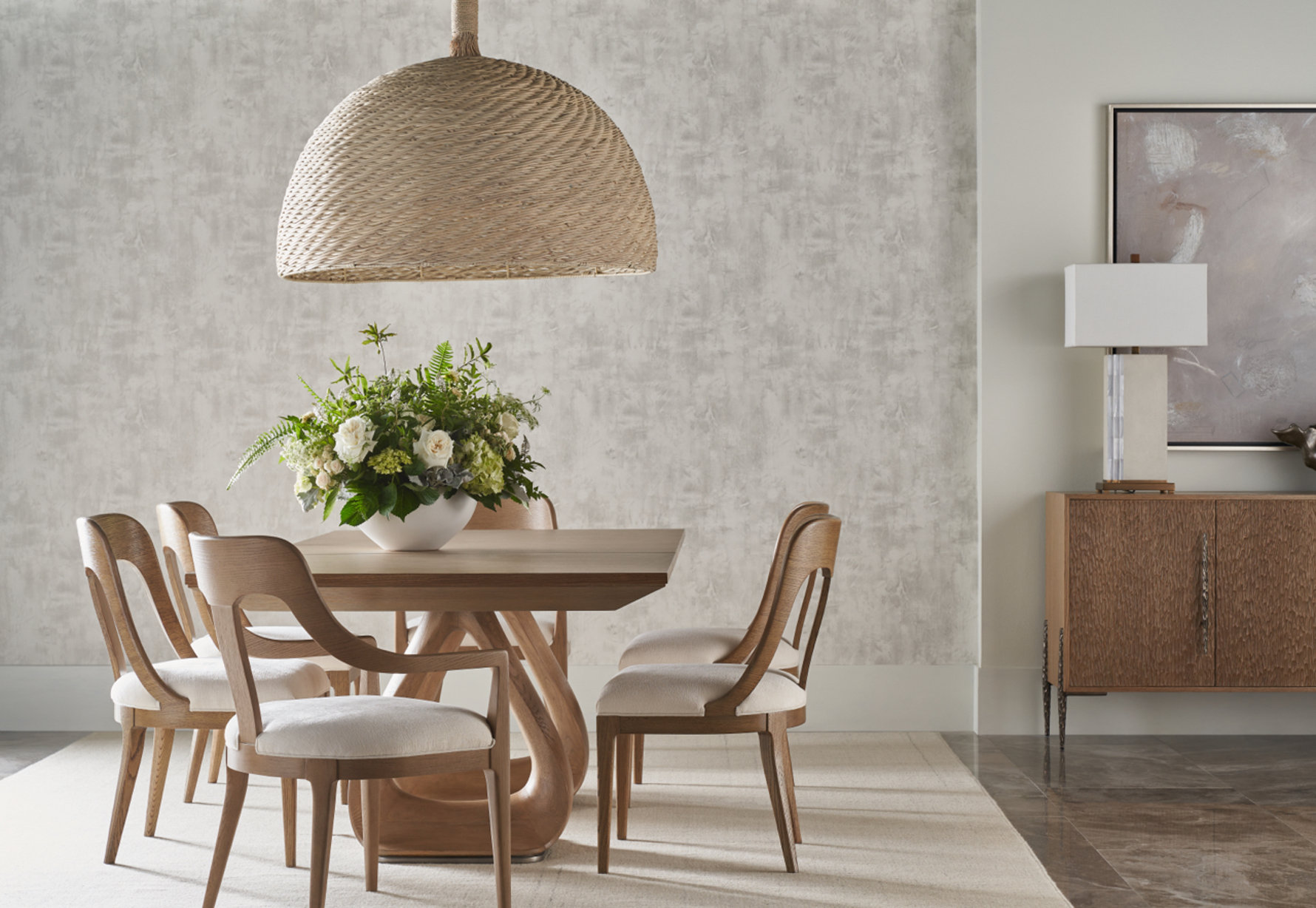 Dining room featuring wooden chairs and a floral centerpiece under a woven pendant light.