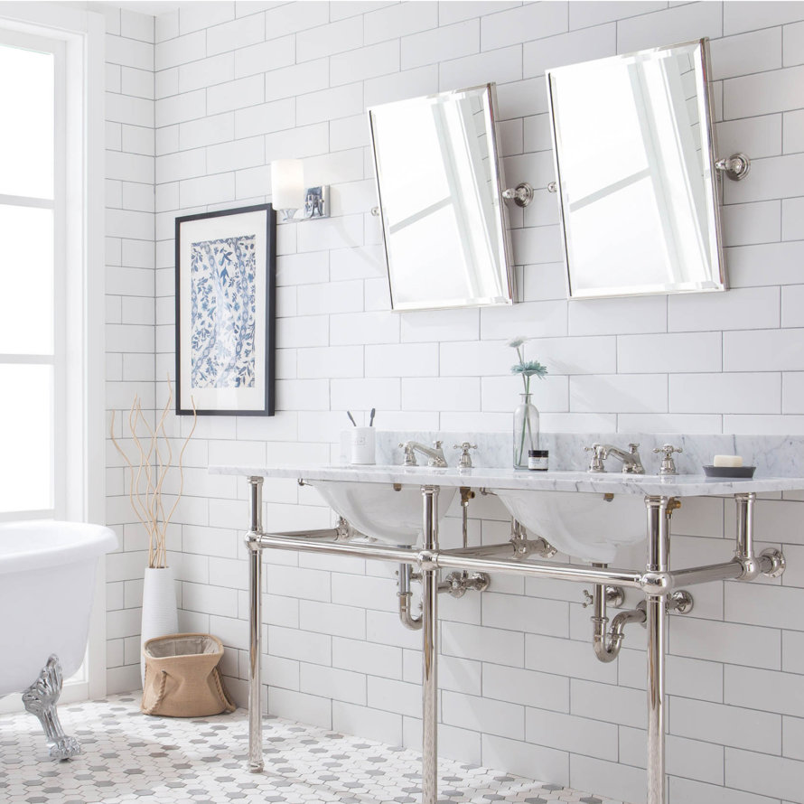 Bathroom with double vanity sink, white subway tile, and clawfoot tub.
