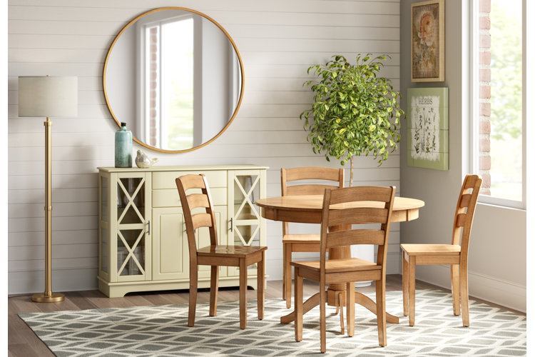 four medium wood ladder back chairs around a matching round table in a modern farmhouse dining room