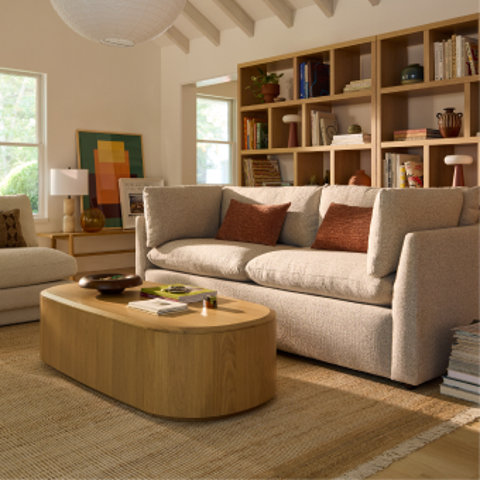 Modern living room with a boucle sofa, oval wood coffee table and styled bookshelf