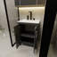 Une armoire de salle de bain noire de 24 pouces, jumelée à un lavabo en céramique blanche, présente un design moderne et est faite de matériaux imperméables et durables