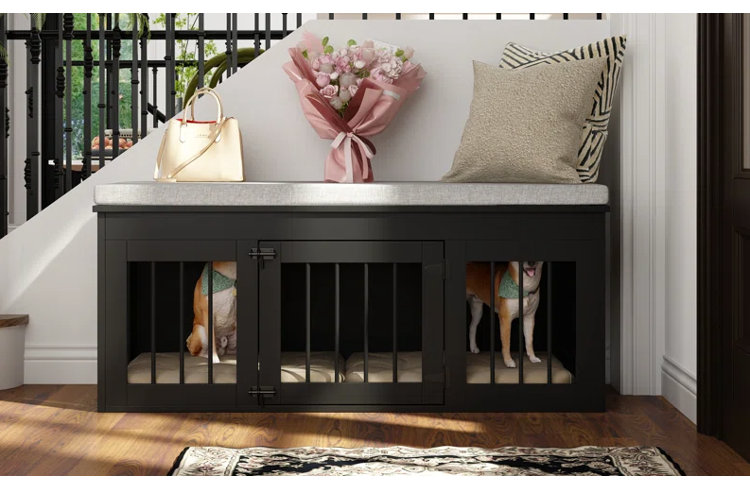 A multi-functional black wood furniture dog crate designed as an entryway bench with a gray cushioned seat, tucked underneath a staircase while a dog is visible inside behind metal bars