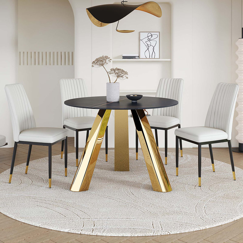 Une table de salle à manger ronde de 42 pouces avec un plateau en granit et des pieds en acier inoxydable, jumelée à quatre chaises de salle à manger en polyuréthane