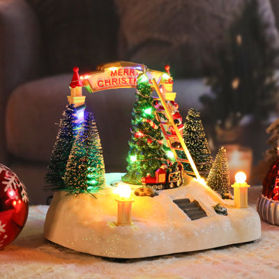 Scène décorative de village de Noël avec Père Noël grimpant, arbre éclairé et arche «joyeux Noël» avec décoration de table éclairée à DEL, train tournant, décoration de table, décoration de Noël