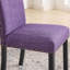 Ensemble de salle à manger Biony en bois avec chaises cloutées en tissu violet, parfait pour des repas de famille chaleureux et élégants.