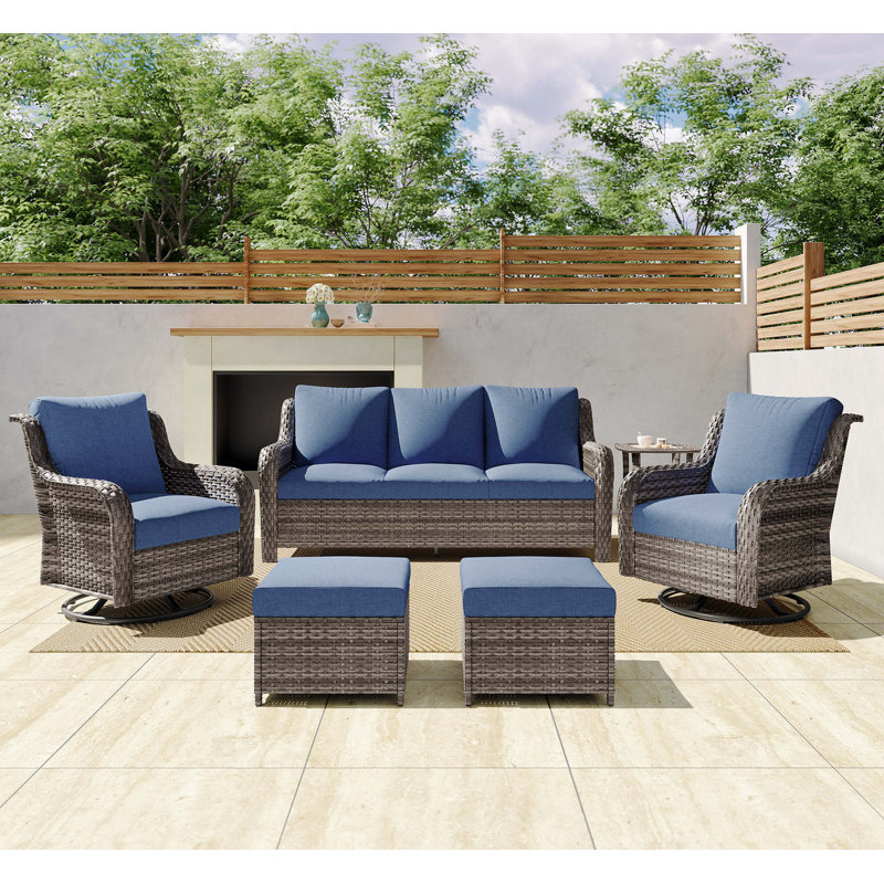 Ensemble de canapé d'extérieur modulaire en osier toutes saisons avec chaises pivotantes, tabourets et table d'appoint en verre trempé pour une vie de patio polyvalente.