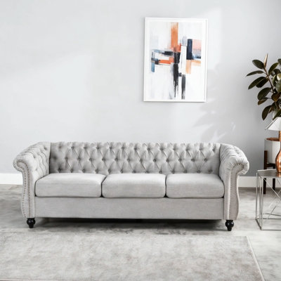 Canapé classique Chesterfield 3 places avec capitonnage à boutons, garniture cloutée et accoudoirs à volutes pour une élégance intemporelle.