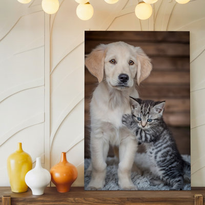 Canvas A Fluffy Golden Retriever Puppy With Soft Pale Fur And Wall Art Expressive Brown Eyes Stands Close To A Small Gray Tabby Canvas Wall Art