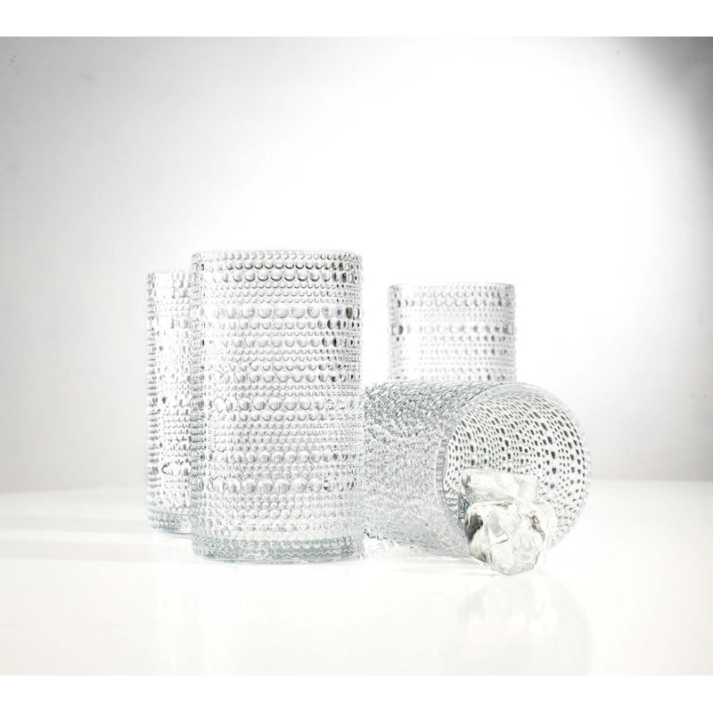 Set of four clear highball glasses with a textured hobnail bead pattern, with one glass shown lying on its side.