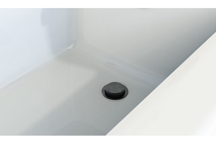 Close-up of a matte black pop-up drain stopper installed on the floor of a white bathtub.