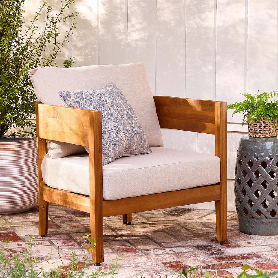 Chaise d'extérieur en bois avec coussins clairs et un coussin décoratif à motifs.