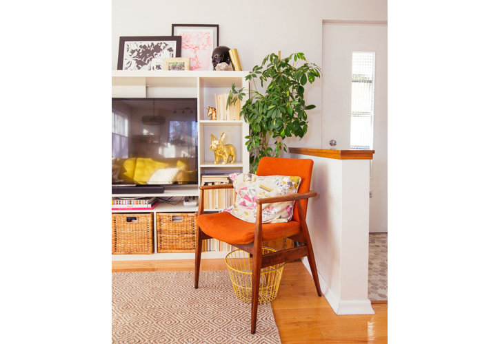 An orange arm chair with a shelving center