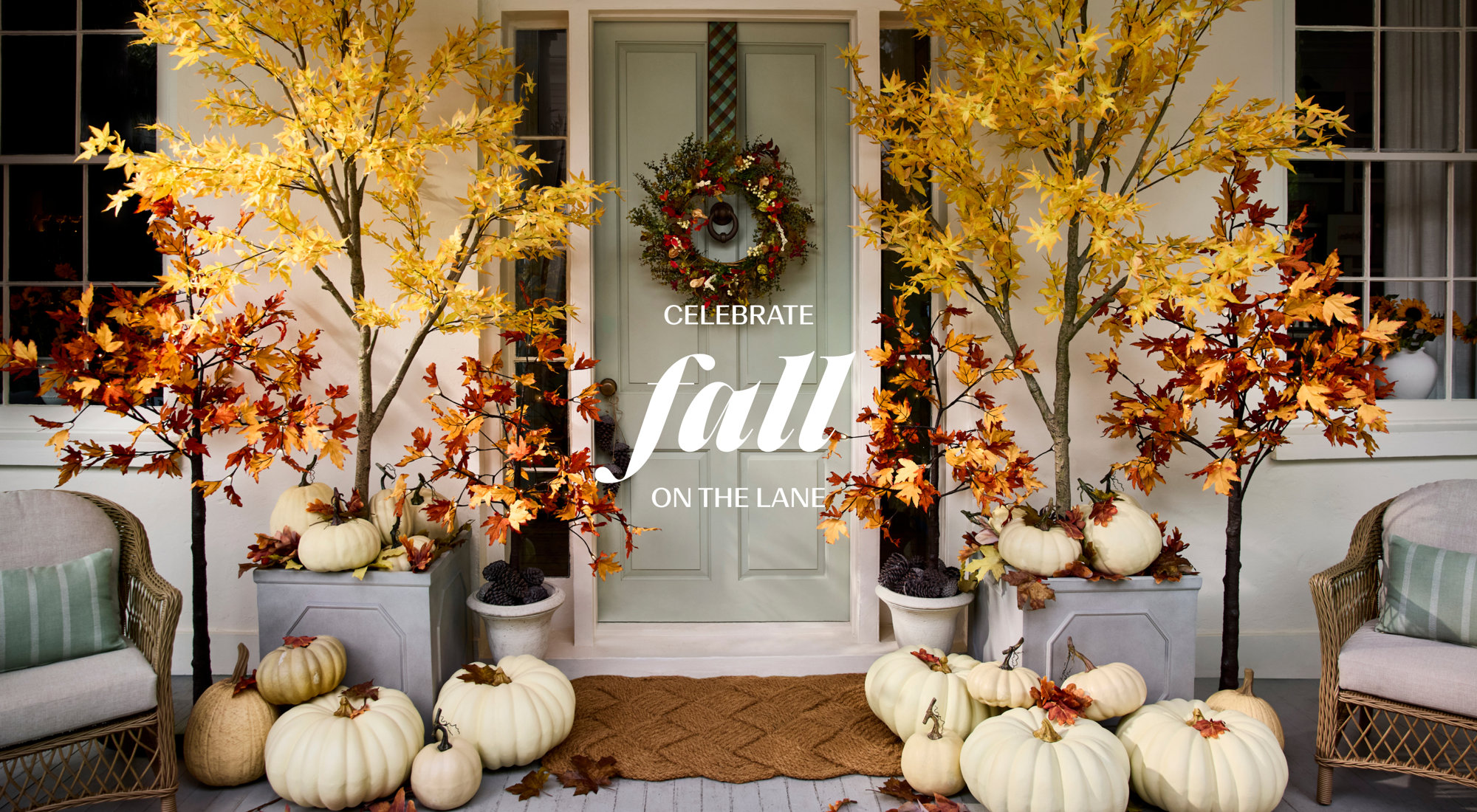 Celebrate fall on the lane with a cozy outdoor patio set featuring wicker furniture, neutral pillows, a fall-themed throw blanket, and a table styled with fruit and refreshments.