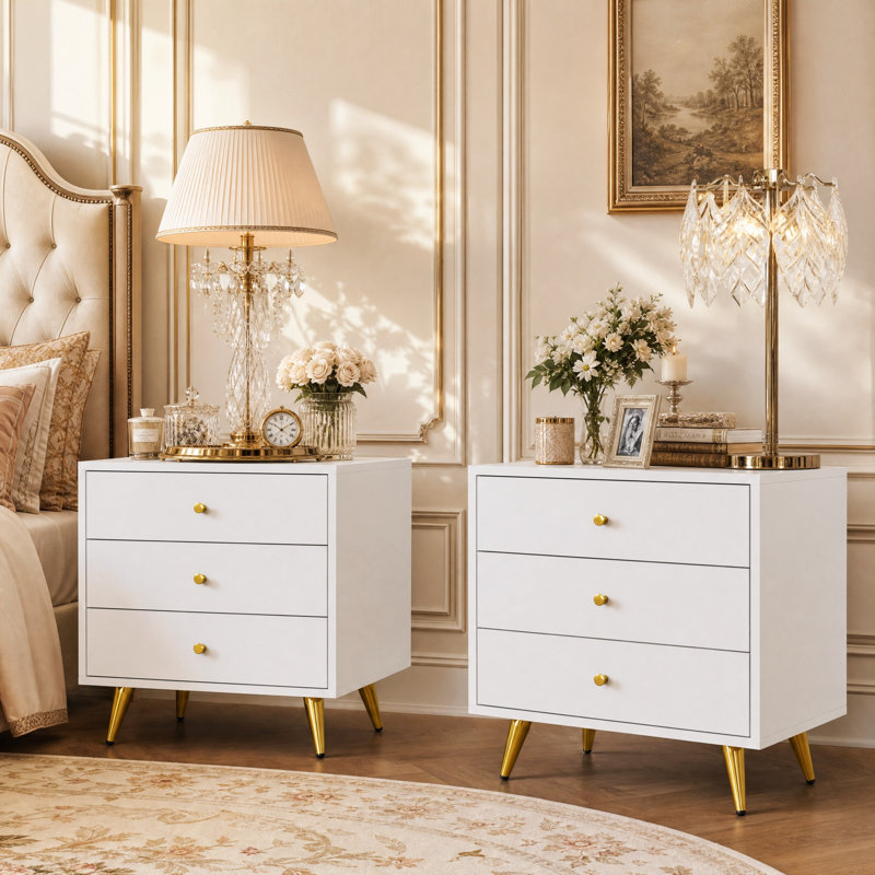 Table de chevet moderne et glamour à 3 tiroirs de 50 cm de large, avec pattes et poignées en métal doré.