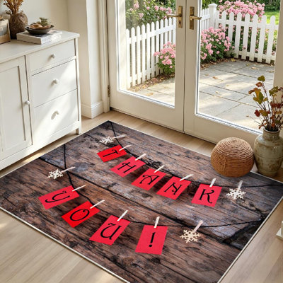 Tapis intérieur rouge lavable à la machine, avec étiquette « Merci » accrochée à une corde à linge.