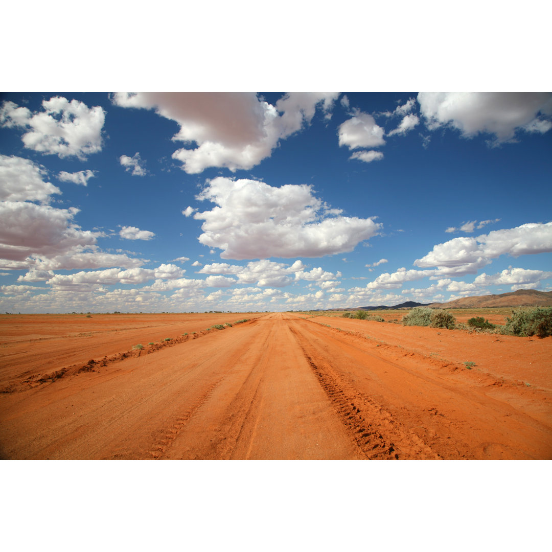 Lange orangefarbene Outback-Straße unter blauem Himmel von Bloodstone - Druck auf Leinwand ohne Rahmen