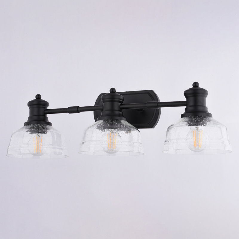 Adakia 3-Light 25.5 In. Wide Matte Black Farmhouse Bathroom Vanity Lighting Fixture, Clear Seeded Glass Shade, Dimmable, LED Compatible, Reversible Over The Mirror Mounted Steel Wall Sconce