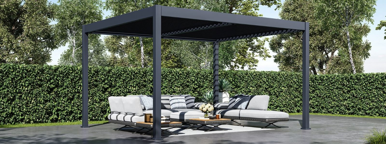 Pergola à lames orientables gris foncé de style moderne couvrant un coin salon sur la terrasse avec un canapé sectionnel gris et des tables basses dans une cour arrière aménagée.
