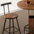 This Walnut Wood Three-Piece Bar Table And Chair Set Features A Round Table With Two Stools And Metal Footrests. It's Compact, Versatile, And Suitable For Small Spaces Such As Dining Rooms, Bars, And Living Rooms.