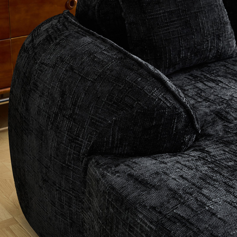 Canapé de coin comprimé en chenille noire, garni de mousse souple haute élasticité, incurvé et doté de quatre coussins décoratifs. Parfait pour le salon et la chambre. Assise mi-ferme, support par ressorts.
