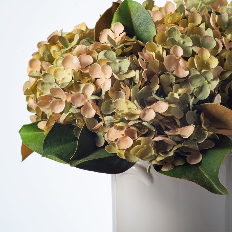 Arrangement quotidien de feuilles d'hortensia vert sauge et de magnolia réel dans un vase de style maison de campagne en céramique blanche