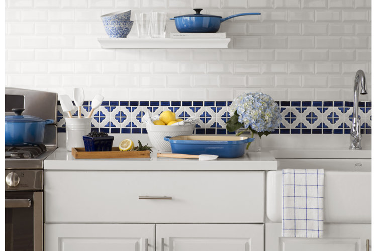 Kitchen with white cabinets and sink and white subway tile and blue patterned backsplash