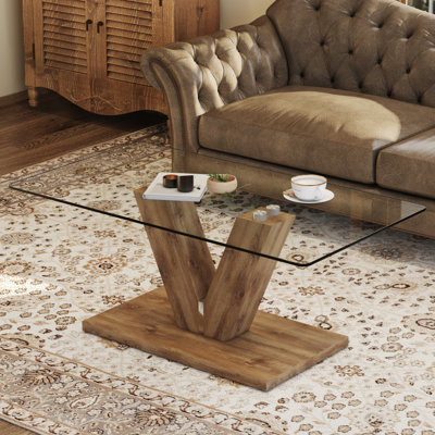 Une table basse de style minimaliste moderne. Plateau de table en verre trempé transparent avec colonnes en bois aggloméré