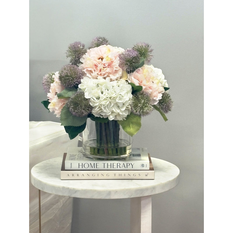 Pivoines avec hortensias et chardon dans un vase en verre