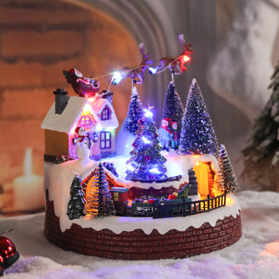 Décor de village de Noël illuminé avec traîneau du Père Noël, renne, bonhomme de neige et train - décoration de table festive avec lumières à DEL pour l'ambiance des Fêtes