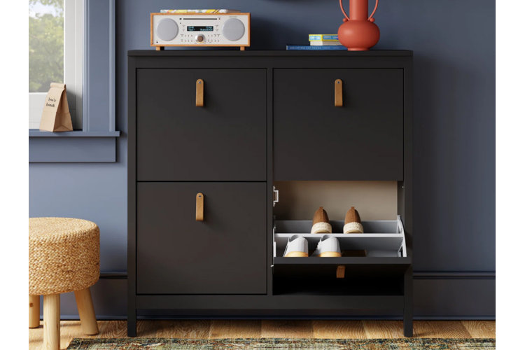 navy shoe cabinet with open door displaying a range of shoes, top of cabinet decorated with a red vase and retro radio