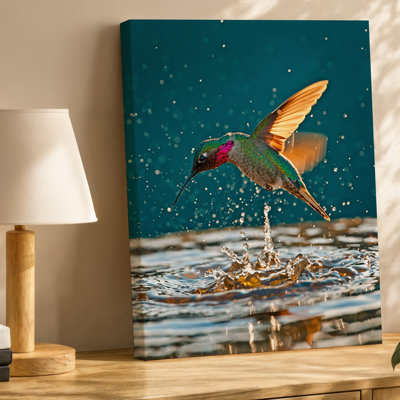 Toile, un colibri vibrant survole gracieusement au-dessus d'une surface d'eau scintillante, ses plumes iridescentes affichant une toile éblouissante