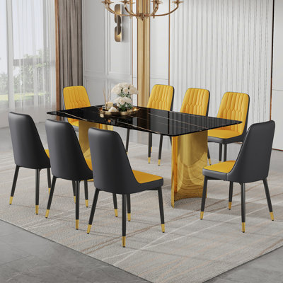 Ensemble de table et de chaises. La table a un plateau en verre avec des autocollants en imitation marbre et des pieds dorés en acier inoxydable. Assorti avec 8 chaises de salle à manger en polyuréthane épissé orange et gris foncé.