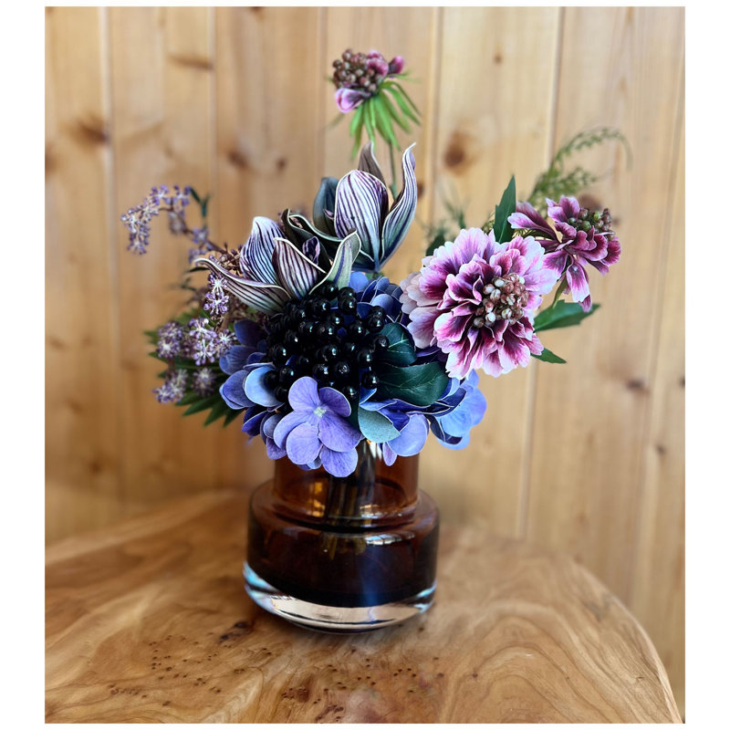 Arrangement de fleurs artificielles dans un vase en verre lesté