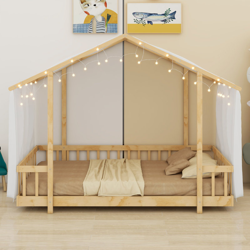 Un lit plateforme avec une structure en forme de maison, un ciel de lit transparent et des lumières scintillantes crée un refuge douillet pour les enfants.