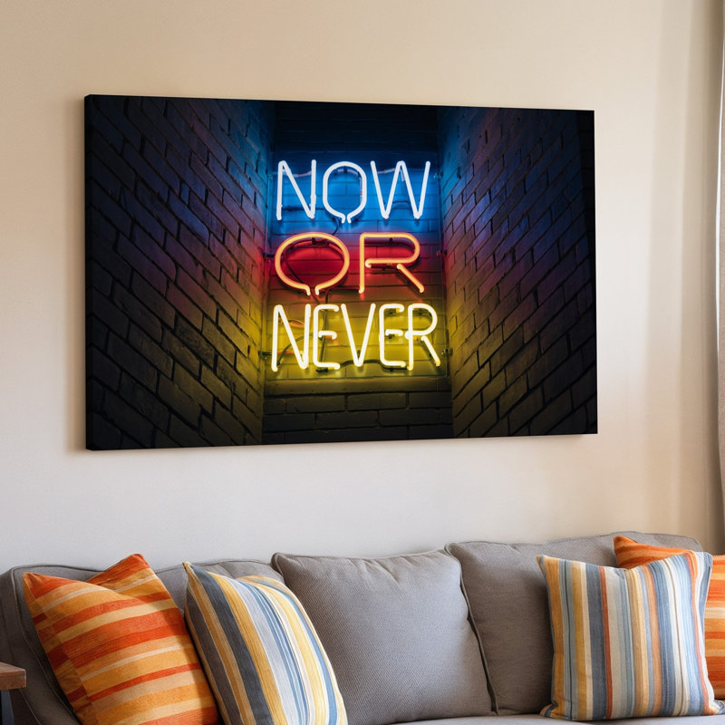 Reproduction d'art sur toile en forme de néon vibrant contre une brique foncée texturée, avec les mots NOW OR NEVER