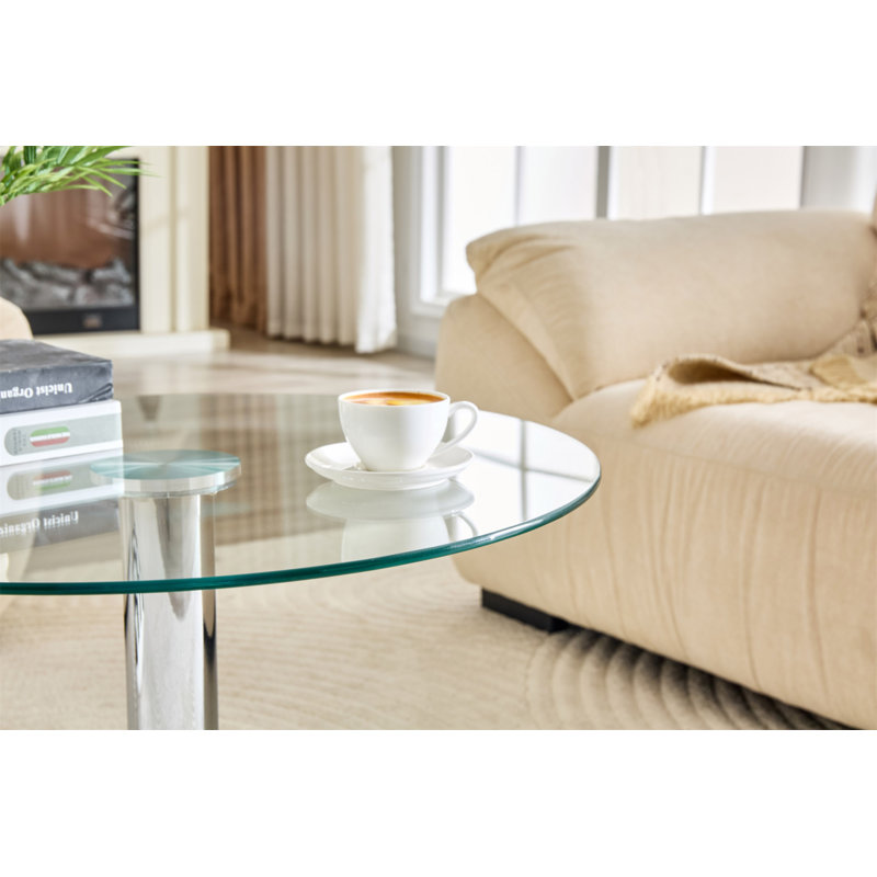 Table basse ronde en verre trempé de 27,5 pouces de diamètre. 17,7 pouces de haut, soutenu par une base en métal argenté, avec un bord de luxe léger.