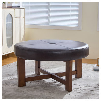 Table basse ronde avec repose-pieds capitonnée en similicuir avec base en bois massif au fini brun foncé et noyer