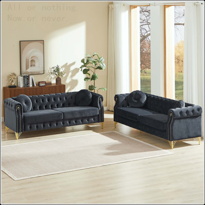 Velvet Chesterfield sofa with two round pillows, featuring copper stud detailing and tufted button accents, with metal legs. Loop design allows for hanging cartoon ornaments.