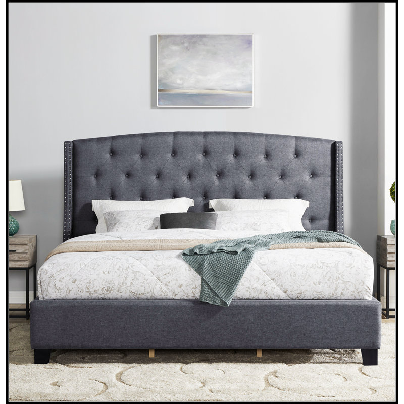 Lit tapissier à oreilles Nantarre en tissu capitonné avec garniture cloutée, alliant confort et élégance pour une expérience de sommeil luxueuse.