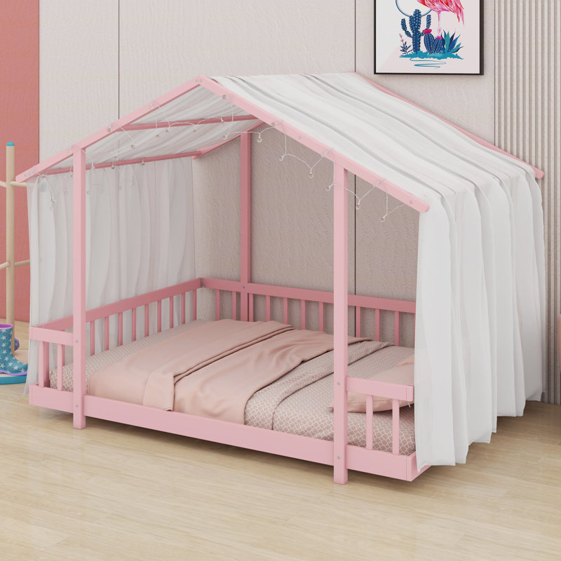Un lit plateforme avec une structure en forme de maison, un ciel de lit transparent et des lumières scintillantes crée un refuge douillet pour les enfants.