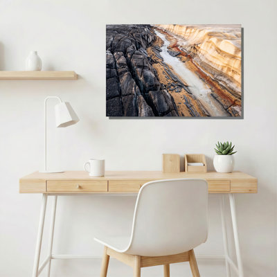 Dark Cracked Rocks And Milky Stream Flowing Past Tan Layers Canvas Wall Art