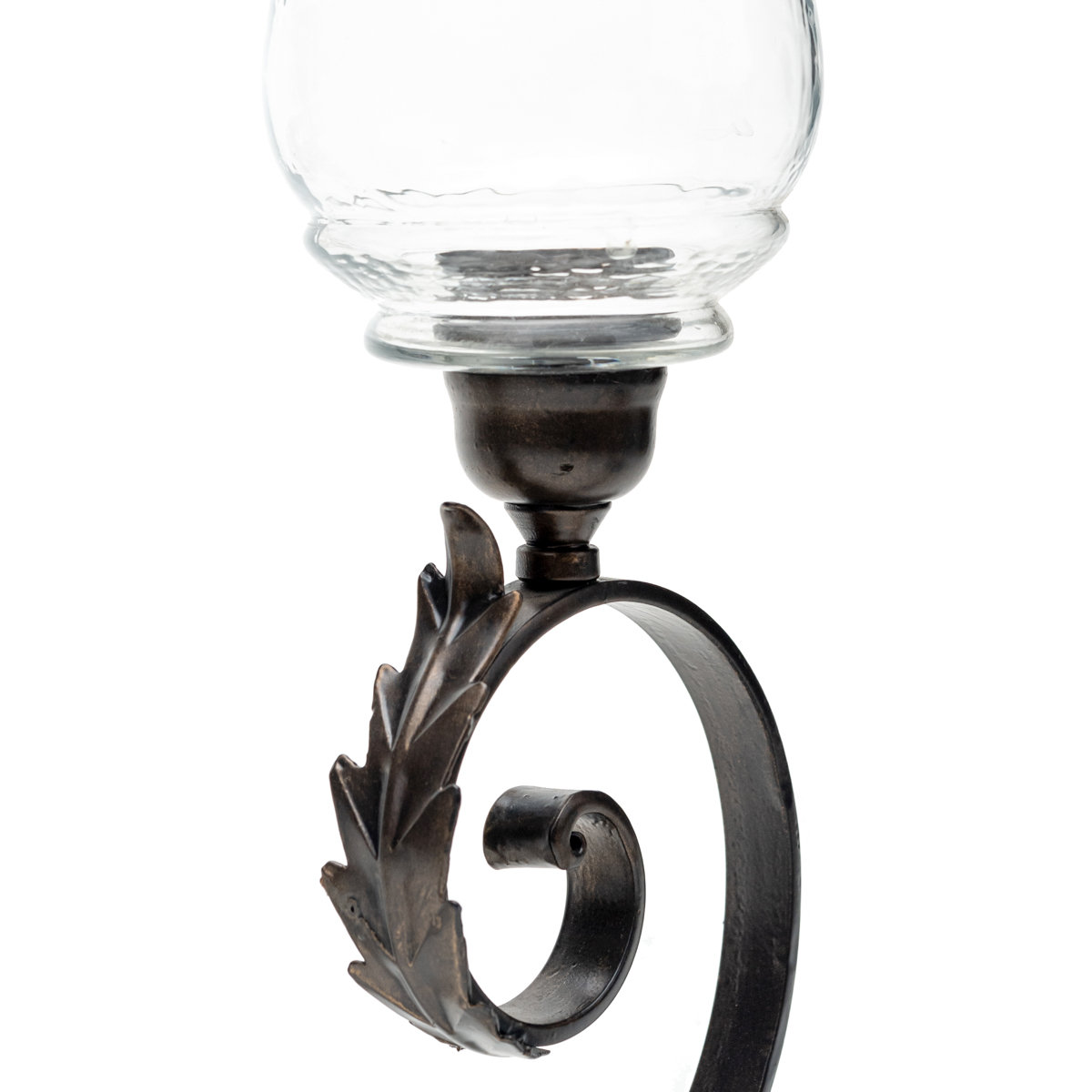 Close-up of a wrought iron candle holder arm with a curled scroll design, decorative leaf accent, and clear glass hurricane shade.